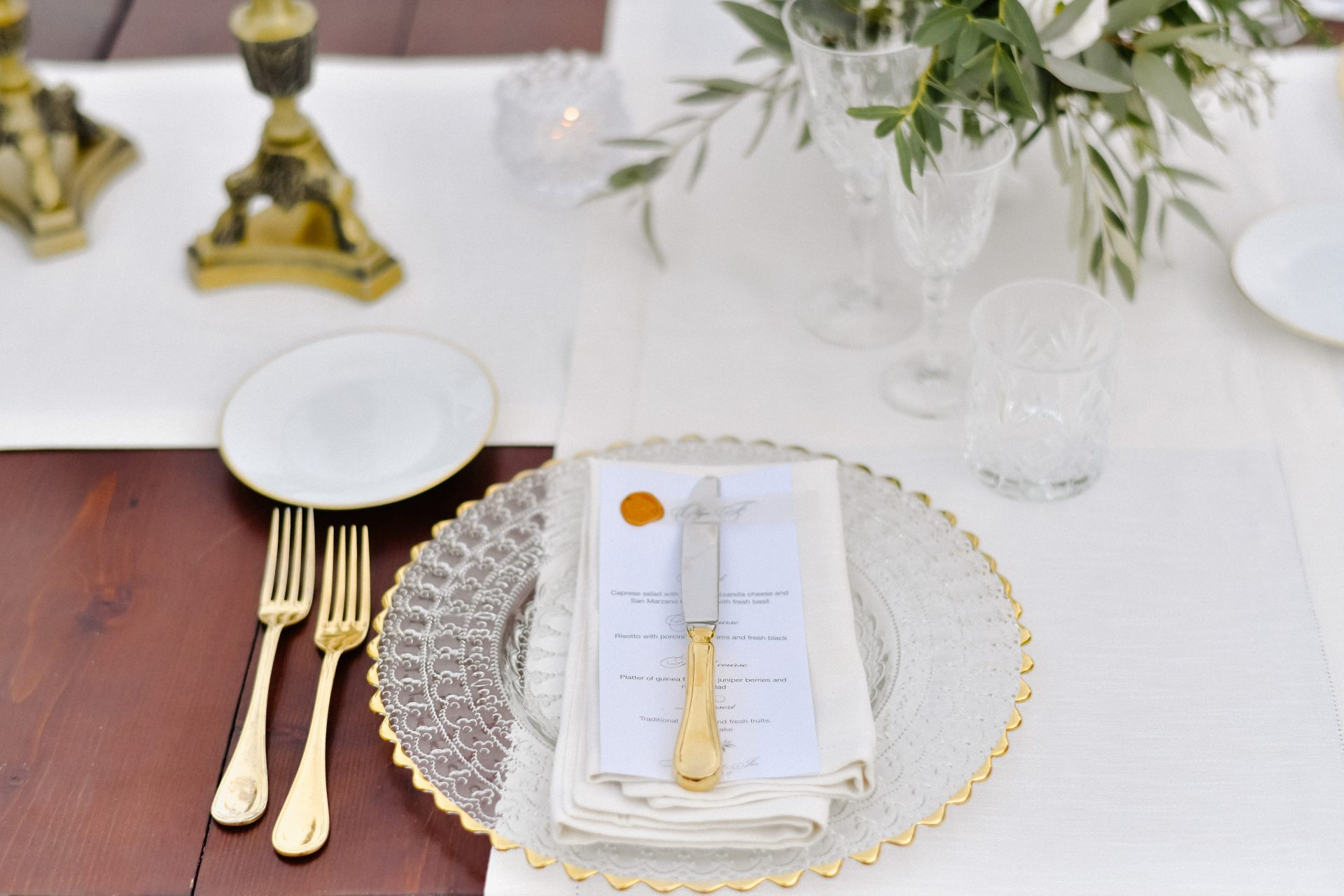 Front view of glassware and golden cutlery served on the wooden